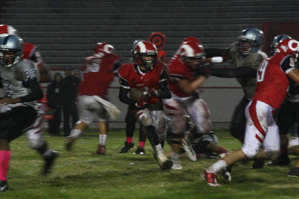 Dishan Romine (12) runs the ball as his teammates hold off the defense. photo by Destony Curry