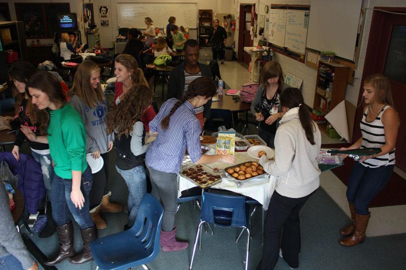 The newspaper staff gather around the tables in room 253, and fill their plates. Photo by Molly Loehr.