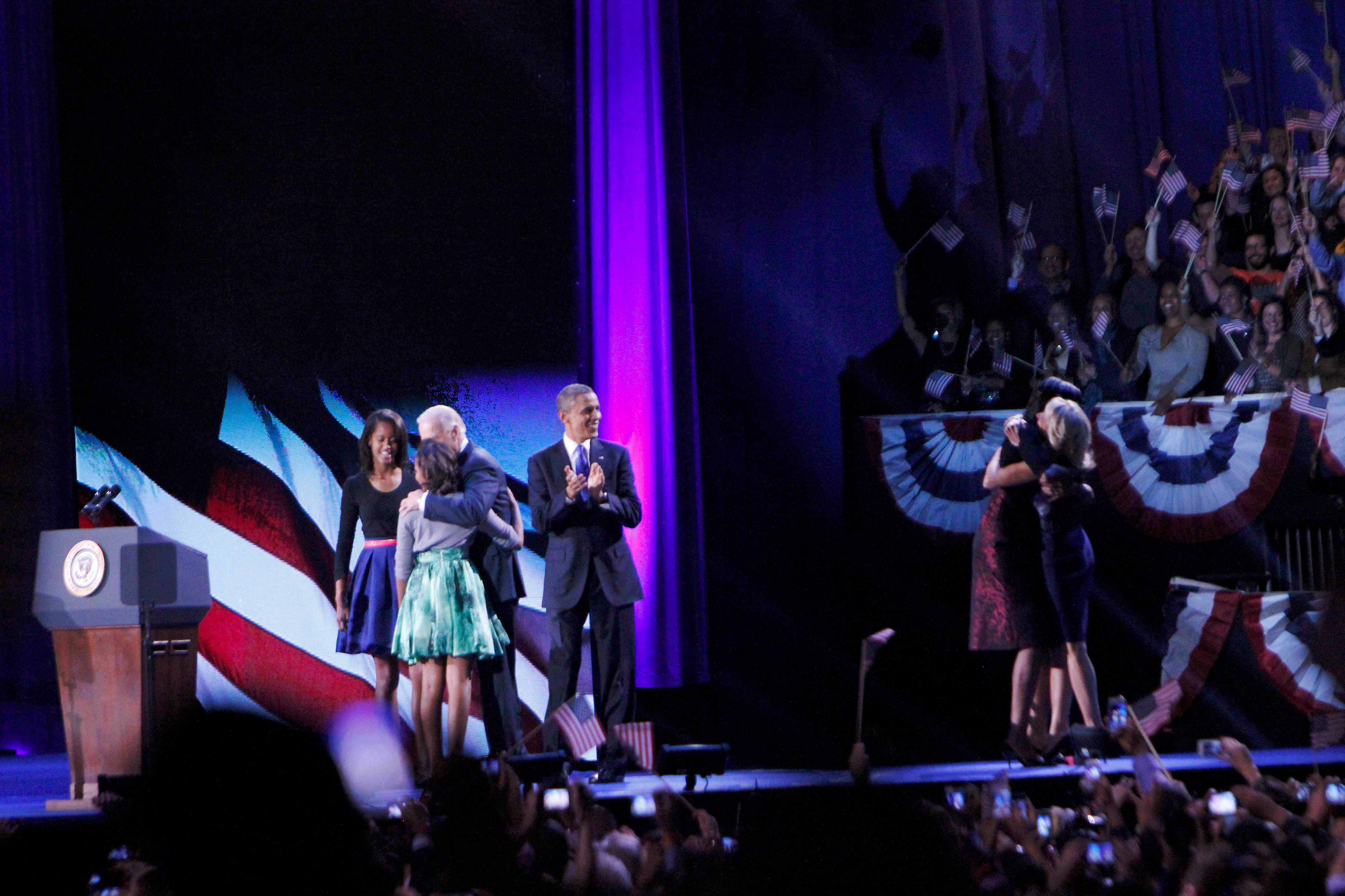 Vice President Joe Biden shares a celebratory hug with President Obamas daughters, Malia (left) and Natasha (right) while Jill Biden and First Lady Michelle Obama embrace one another on the stage of  McCormick Place before the thousands of rally attendees following President Obamas speech.