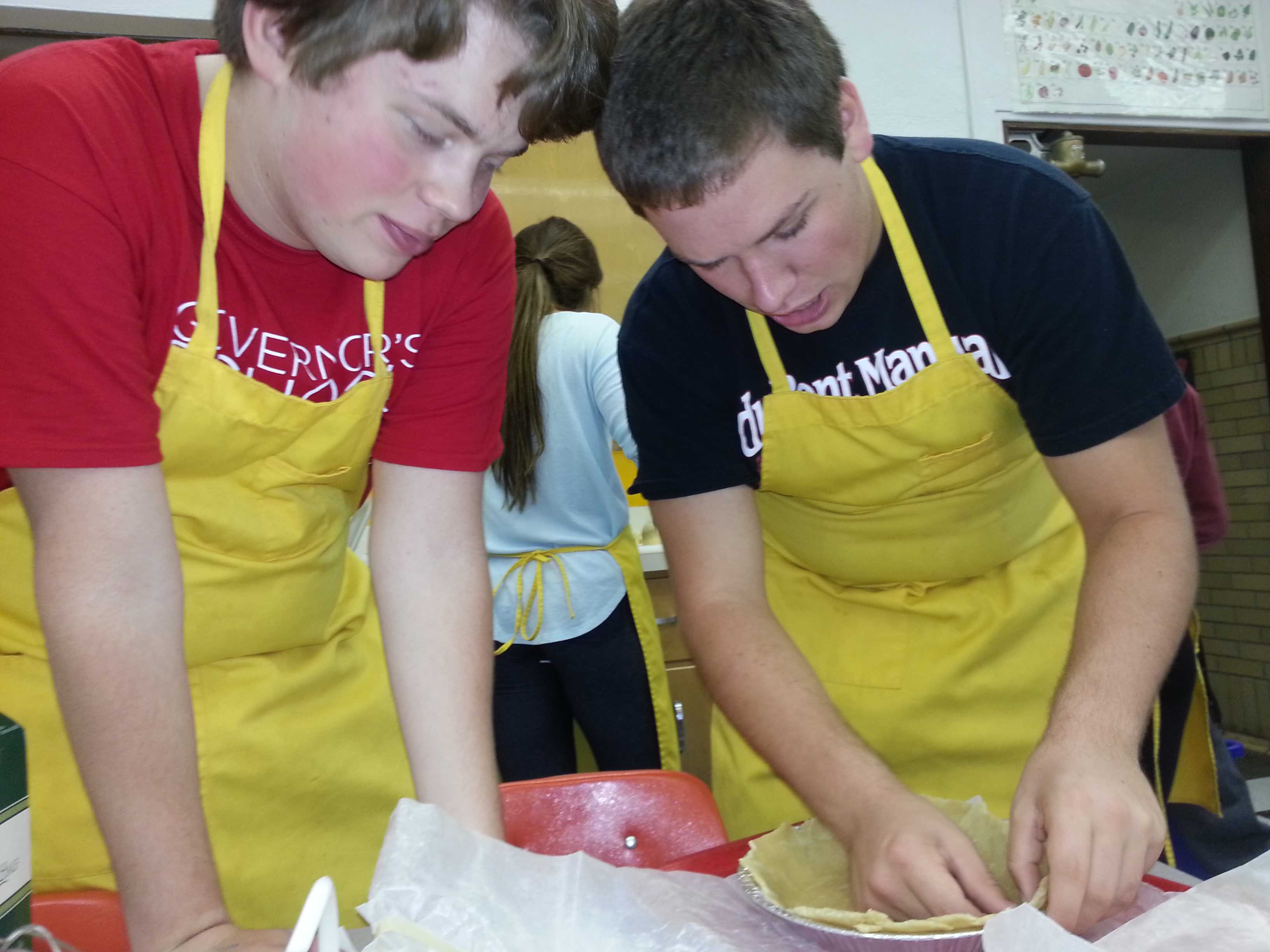 Hunter Schanz and Spencer Crawford line a pie pan with dough during Ms. Cashs R2 Foods class.