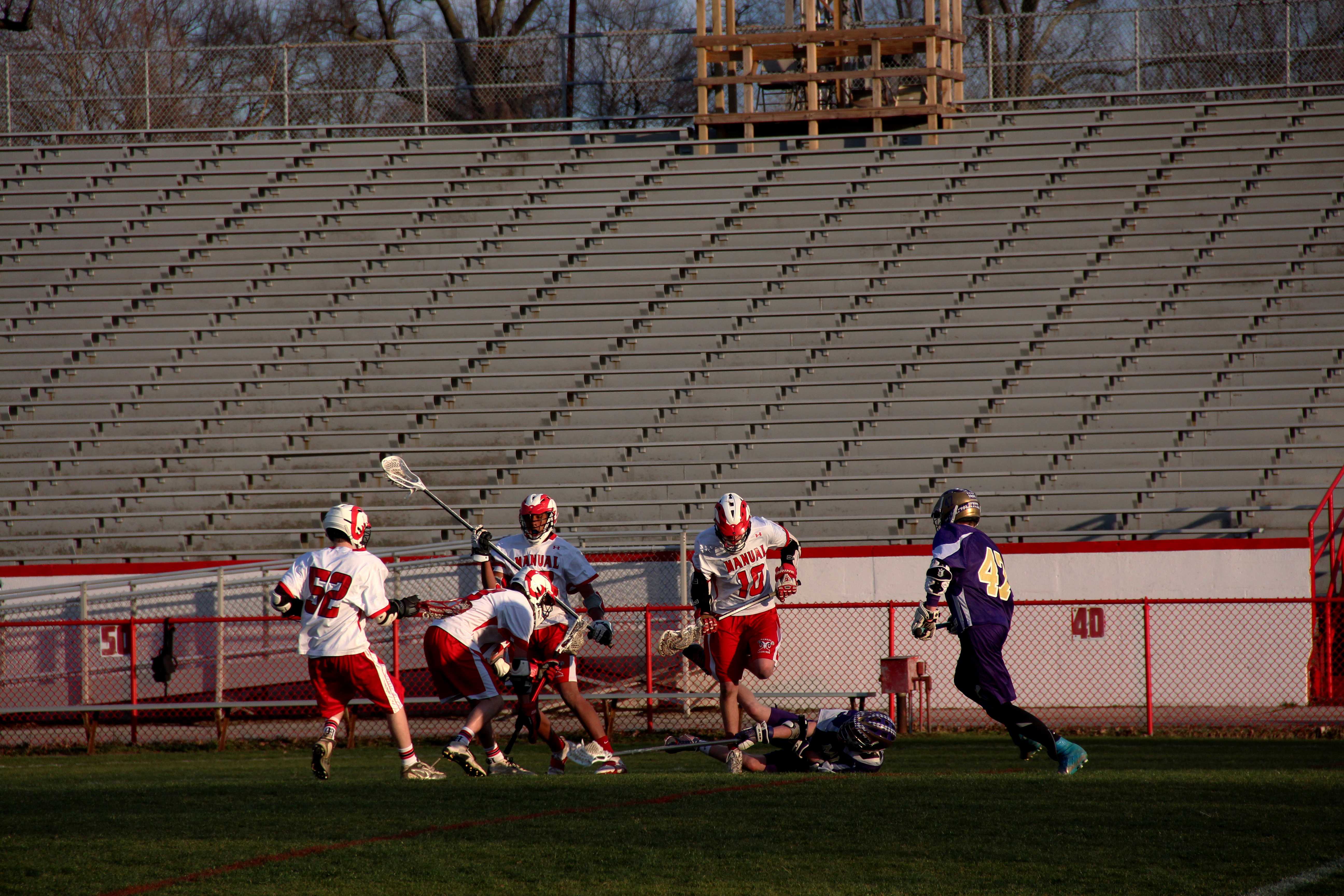 Manuals players battle for the ball as Males player drops the lacrosse ball out of his head.