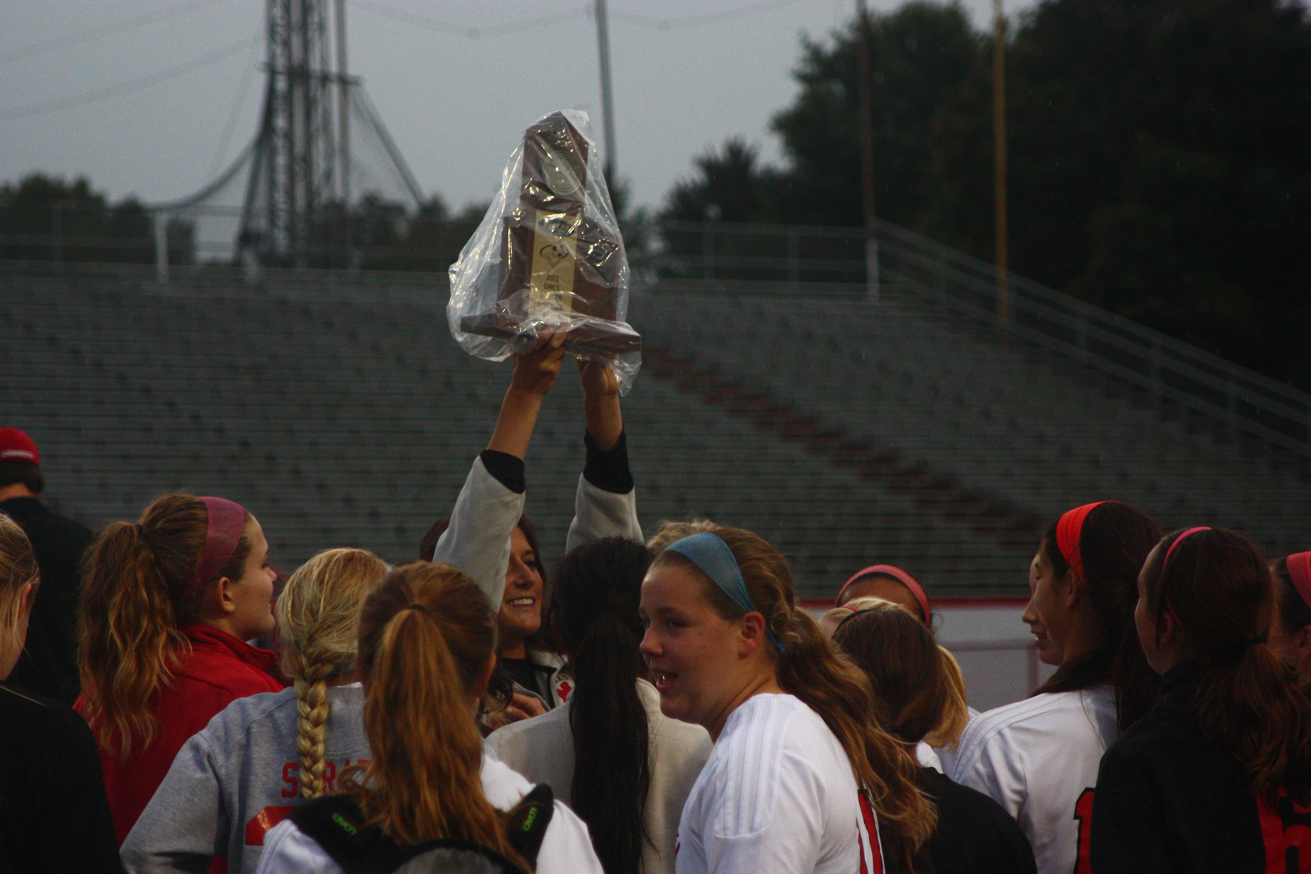 Emily Wilbar hoists the district champion trphy above her team in celebration of their victory over Presentation