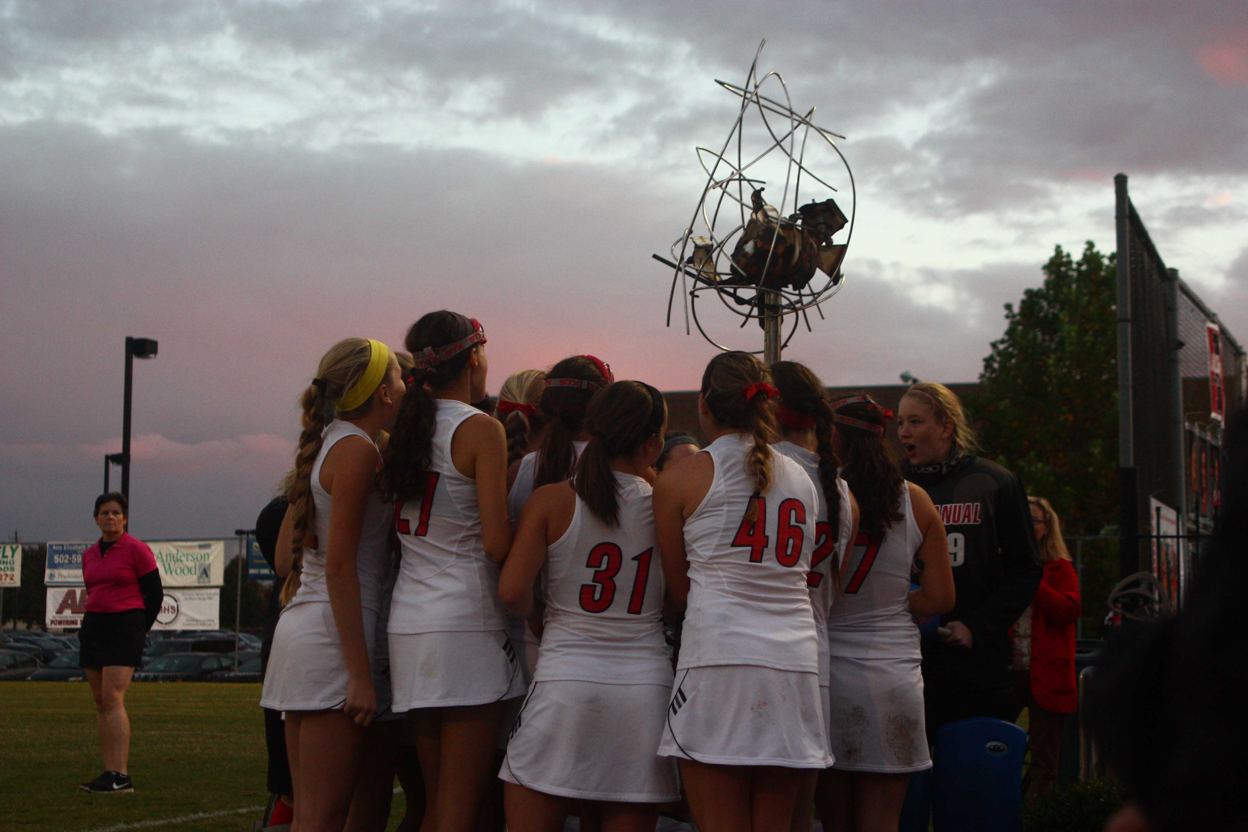Before the game, Manual players sing the school fight song while huddled around a landmark sculpture