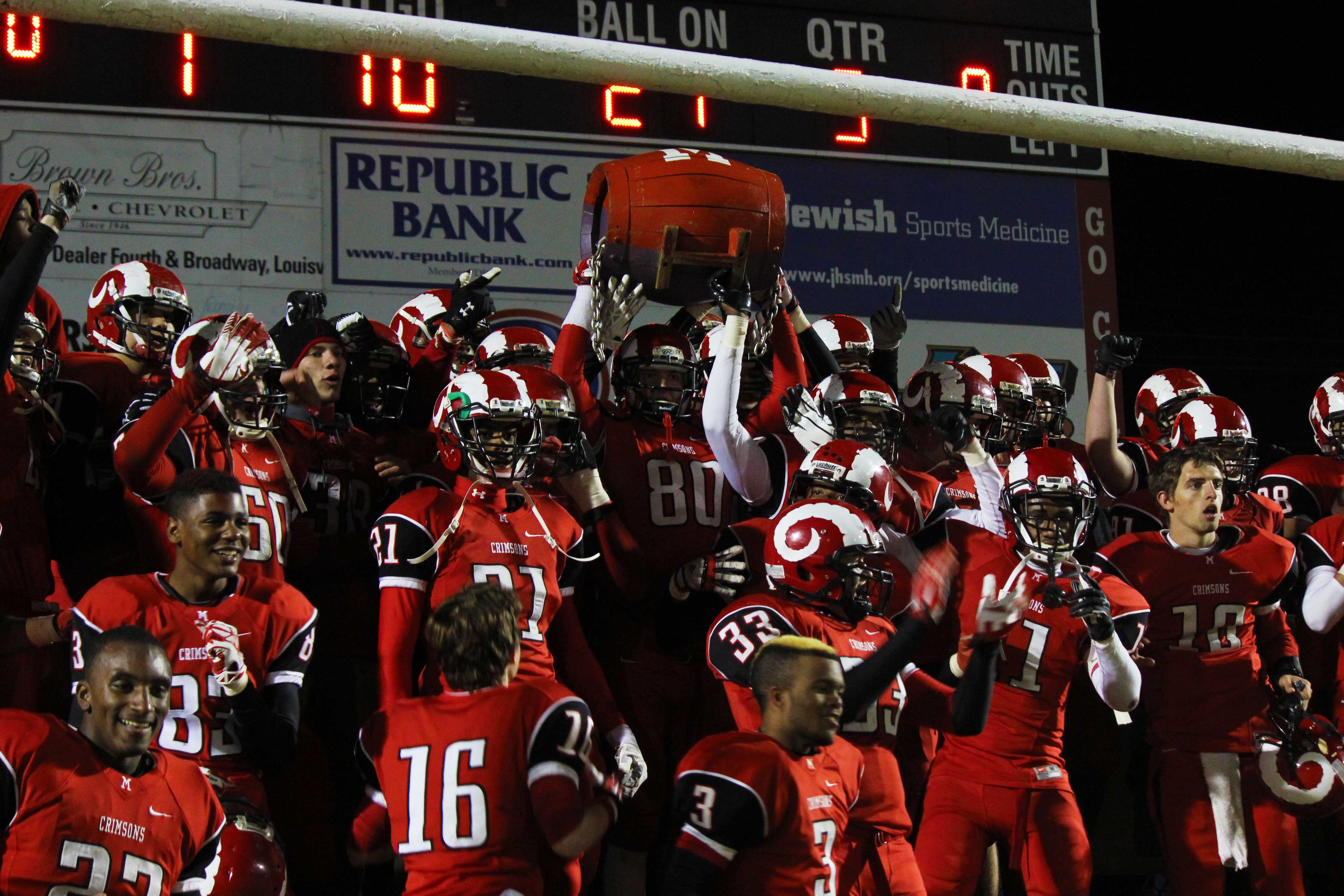 At the end of the game, the football team lines up to take a picture with the barrel right after their win.