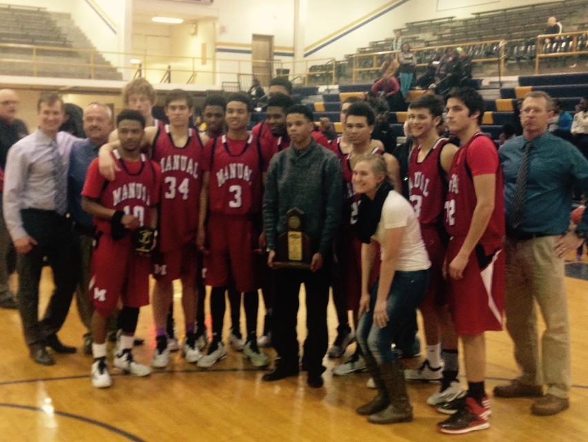 The Manual Boys Basketball team poses with the District 25 Tournament Championship Trophy after defeating Central. Photo by, Jack Grossman