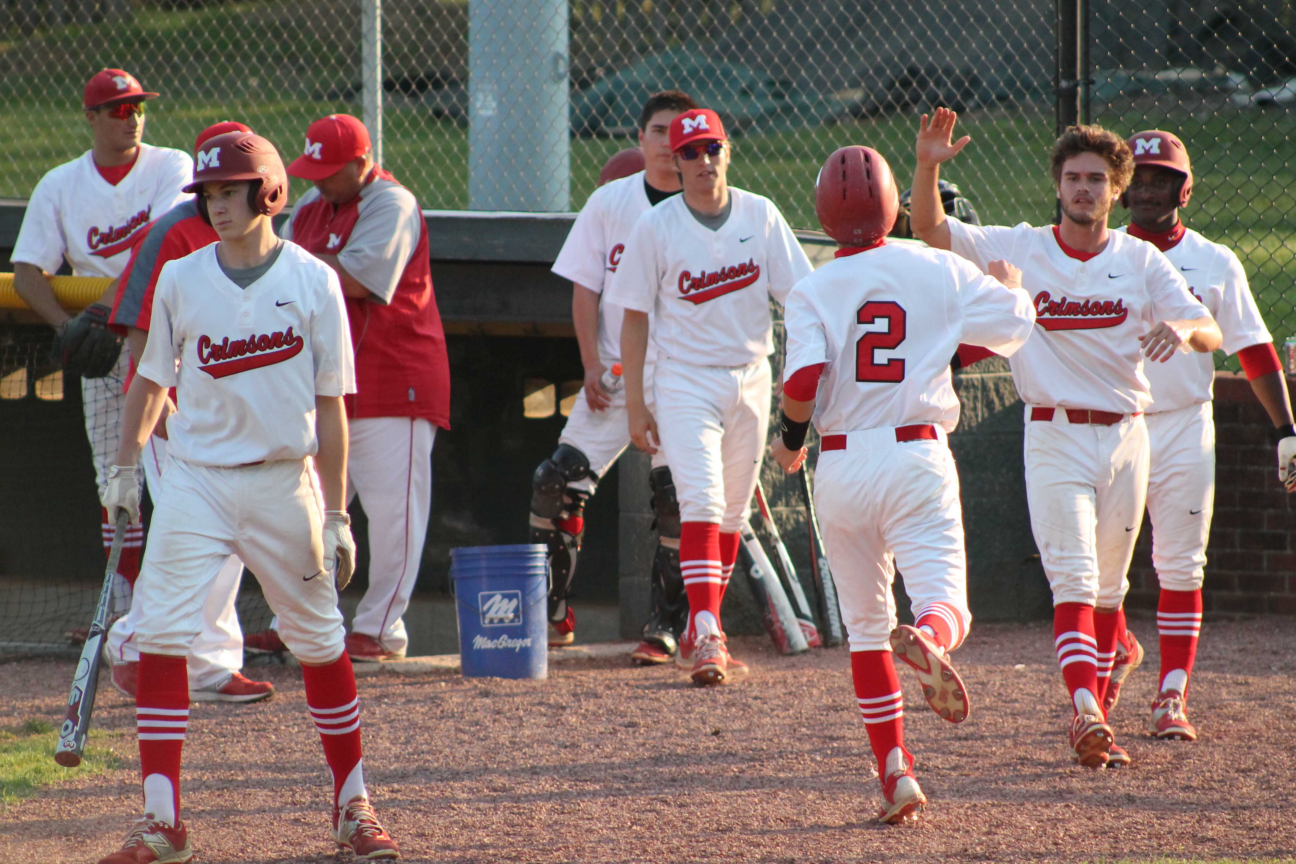 Matt Olson (11, #2) celebrates with Matthew Marino (12, #7) and others after scoring Manuals first run of the game off of a hit by Aaron Sary (9, #20).