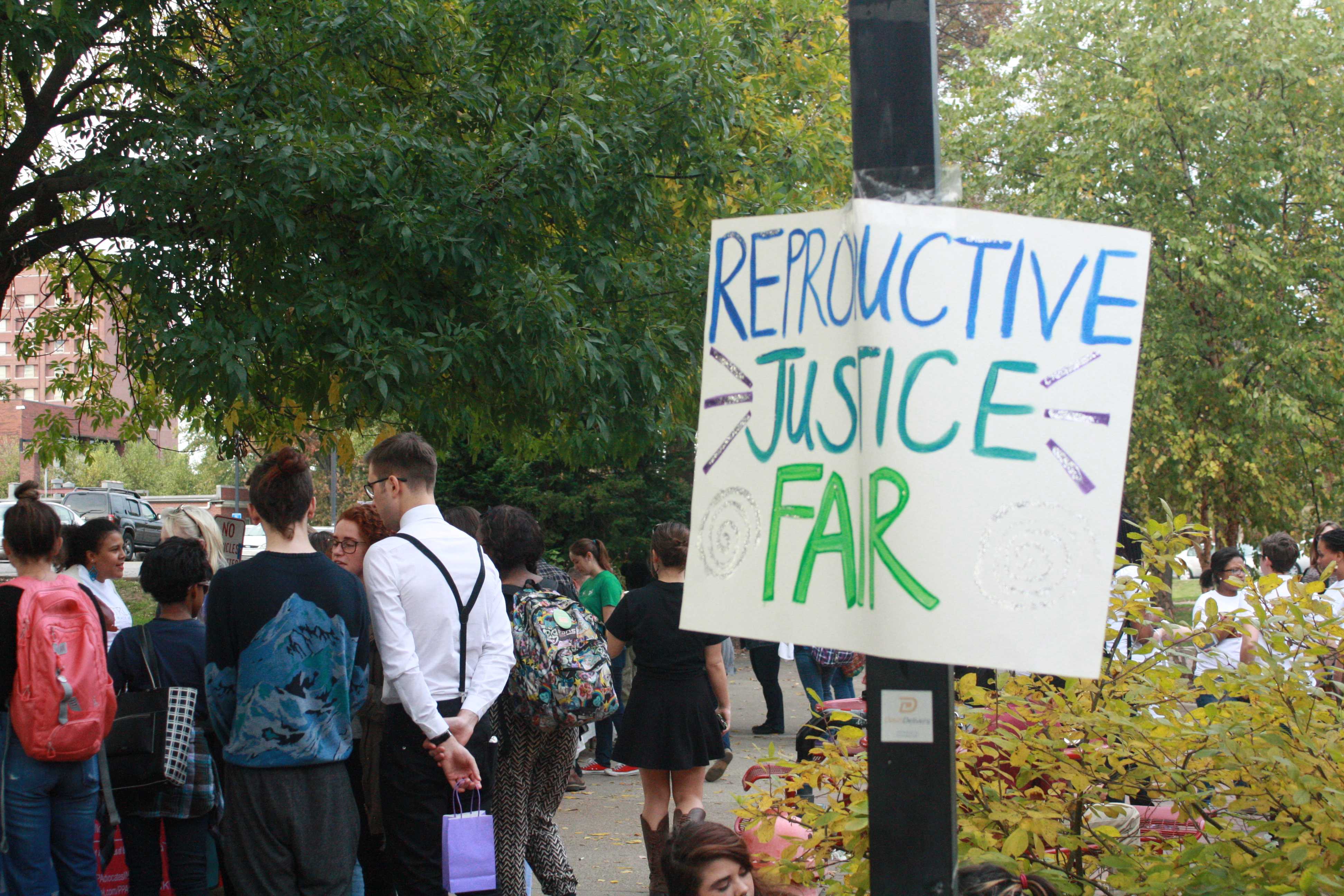 Reproductive Justice Fair sign  hangs on pole. Photo by Phoebe Monsour.