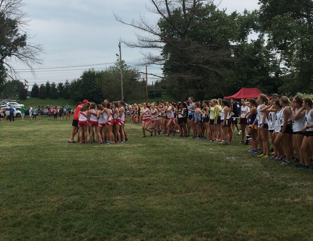 The girls JV team has a team meeting before the start of their race. I definitely saw some really good effort, Zayne Isom (11) said. Picture by Adrienne Sato