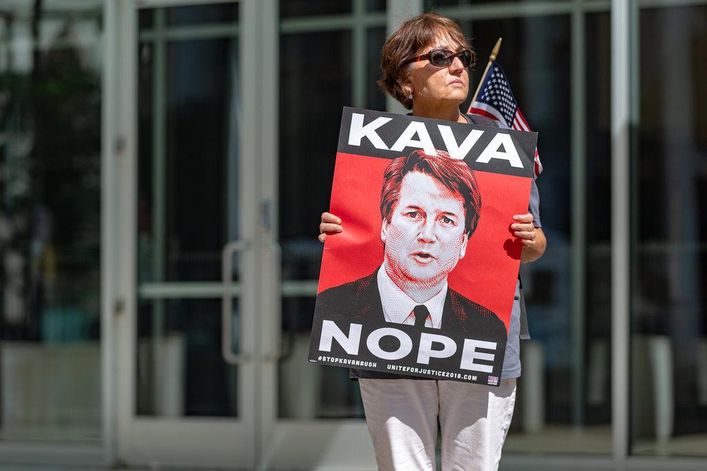A protester against the confirmation of U.S. Supreme Court nominee Brett Kavanaugh outside the Warren E. Burger Federal Building in St. Paul, Minnesota by Lorie Shaull. Image is licensed under Creative Commons Attribution-ShareAlike 2.0 Generic. Use of this photo does not indicate photographer endorsement of this article.