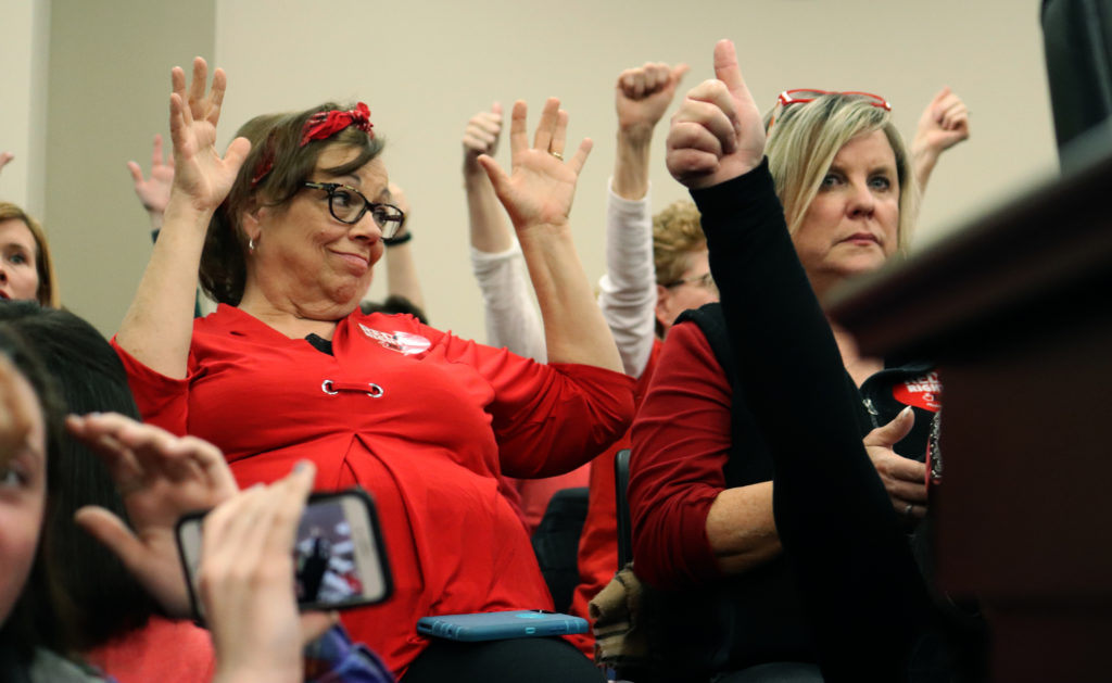 Since the crowd had to stay silent during the meeting, protesters raise their hands to support an opponent of HB 525. Photo by Phoebe Monsour.