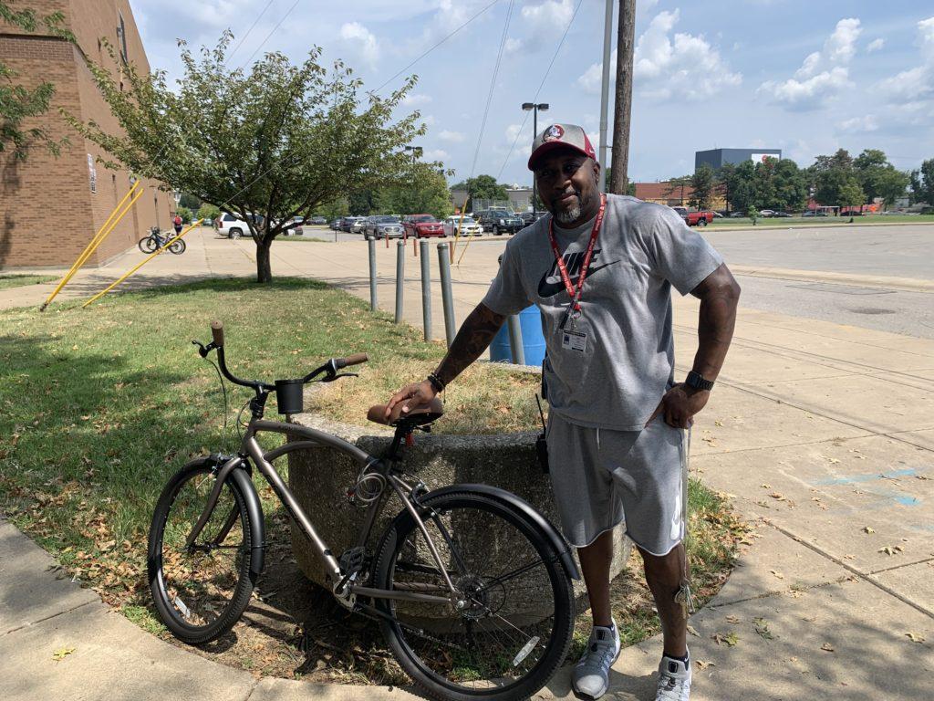 Mr. Cox poses in front of the bike he rides between Manual and YPAS while making sure students are safe walking between the two buildings. Photo by Reece Gunther.