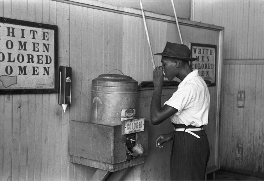 A man drinks at a water fountain that is separated from the white water fountain. Photo from  Library of Congresss Prints and Photographs division.