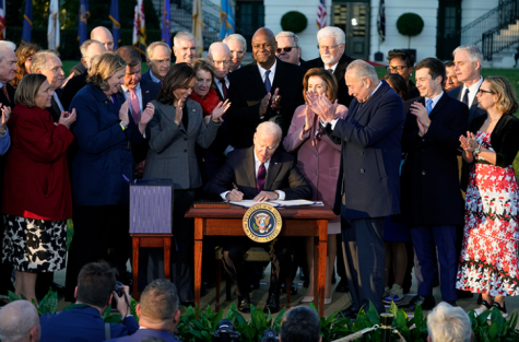 Biden receives a round of applause as he finishes signing the bill.