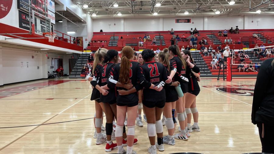 The volleyball team huddles close in preparation for their game