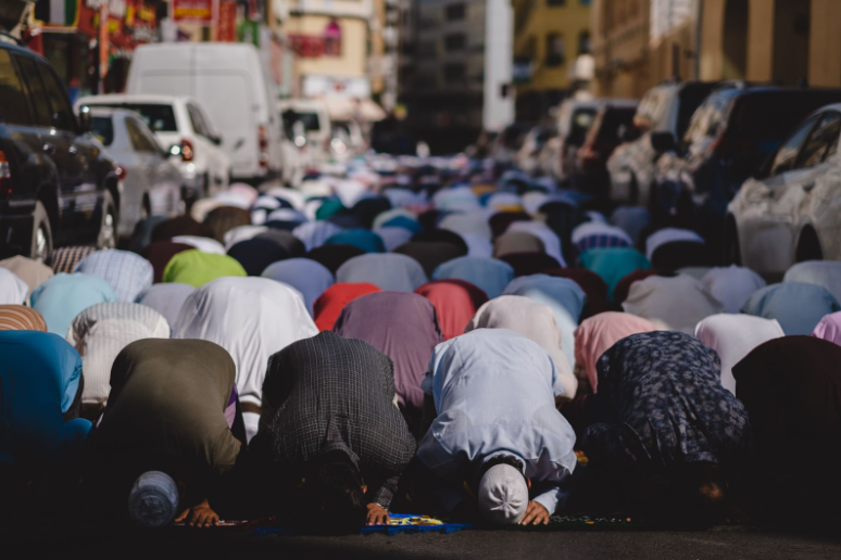 A congregation of Muslims praying in Dubai has spilled onto the road outside of the mosque. Photo courtesy of unsplash