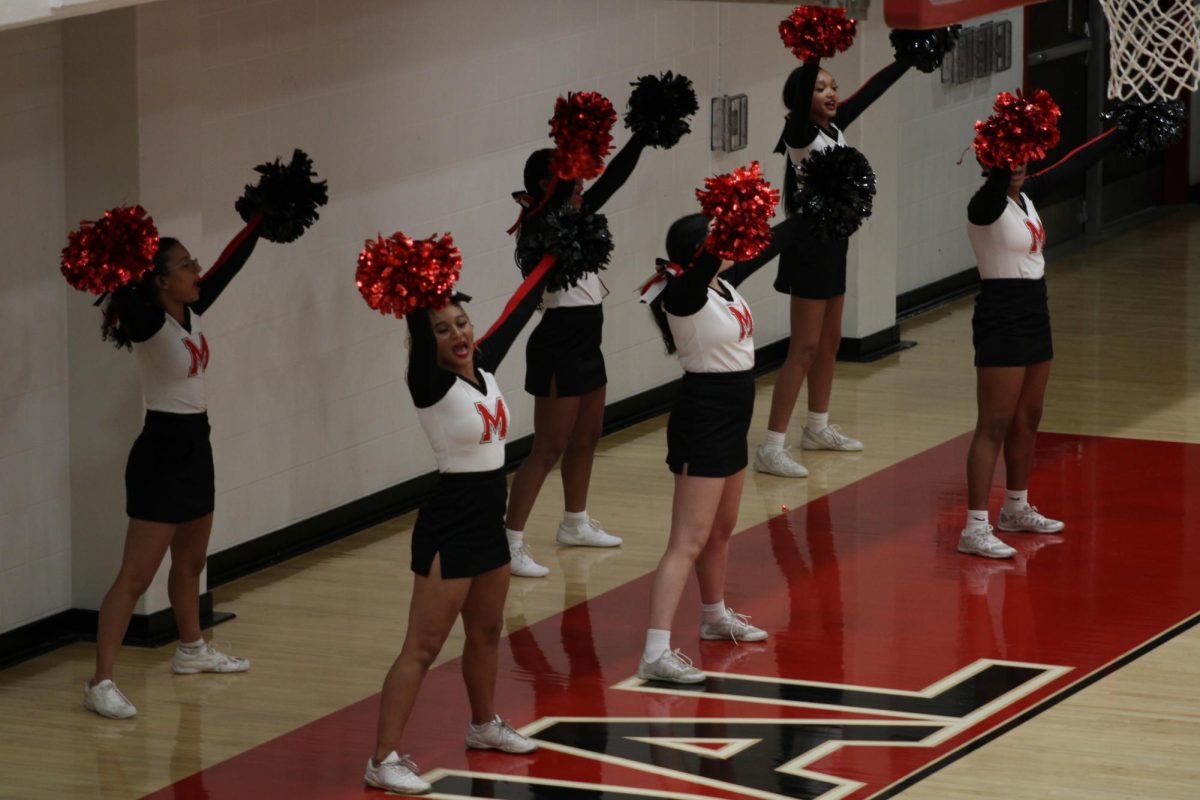 Some of Manual’s cheerleaders cheer on the sidelines. Photo by Katie Dikes