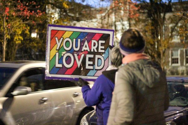 Counter-protestors holding a sign that says You are Loved as cars pass by. Photo by Ava Blair