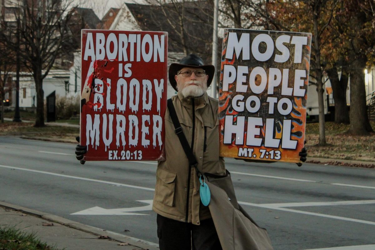 A member of the Westboro Baptist Church holding signs on the street.