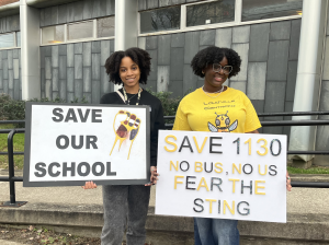 Central High School 11th graders Jeylin Cano Solis (left) and Anaya Coleman (right) hold up signs in front of the Van Hoose center. Photo by Lydia Morgan