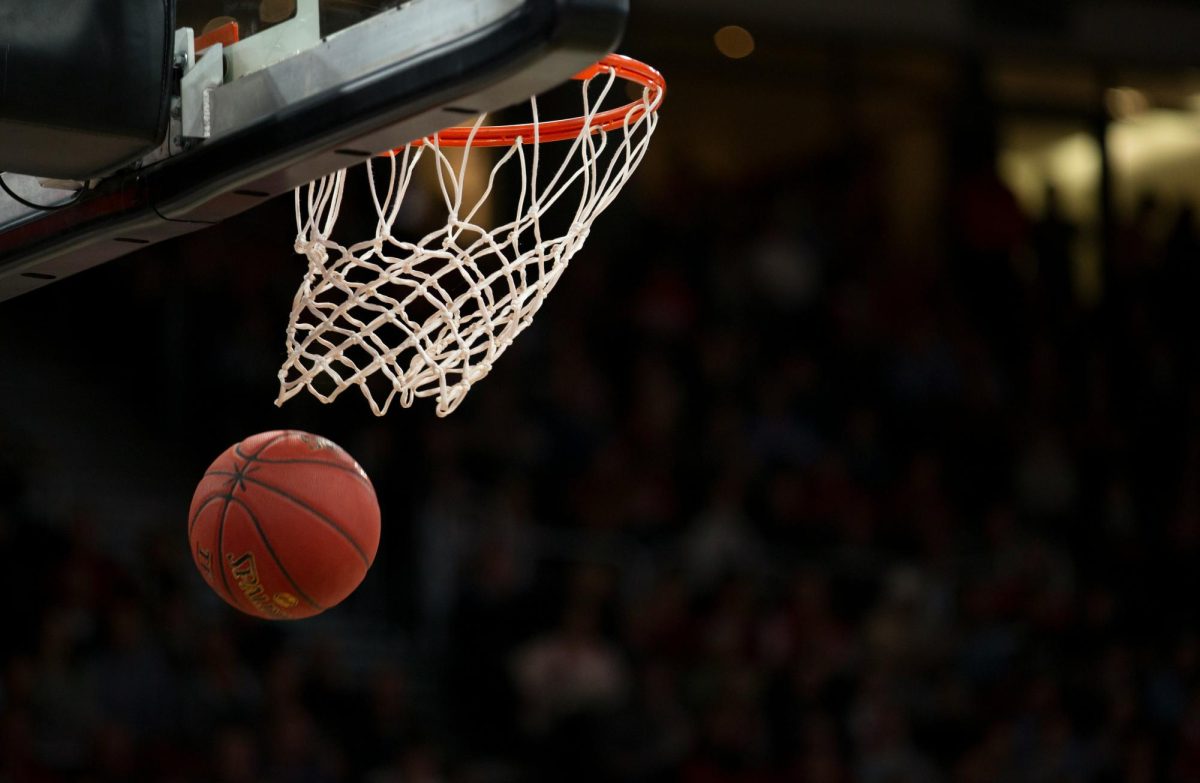 A ball flying through the basket during a college basketball game. Photo by Markus Spiske on Unsplash
  