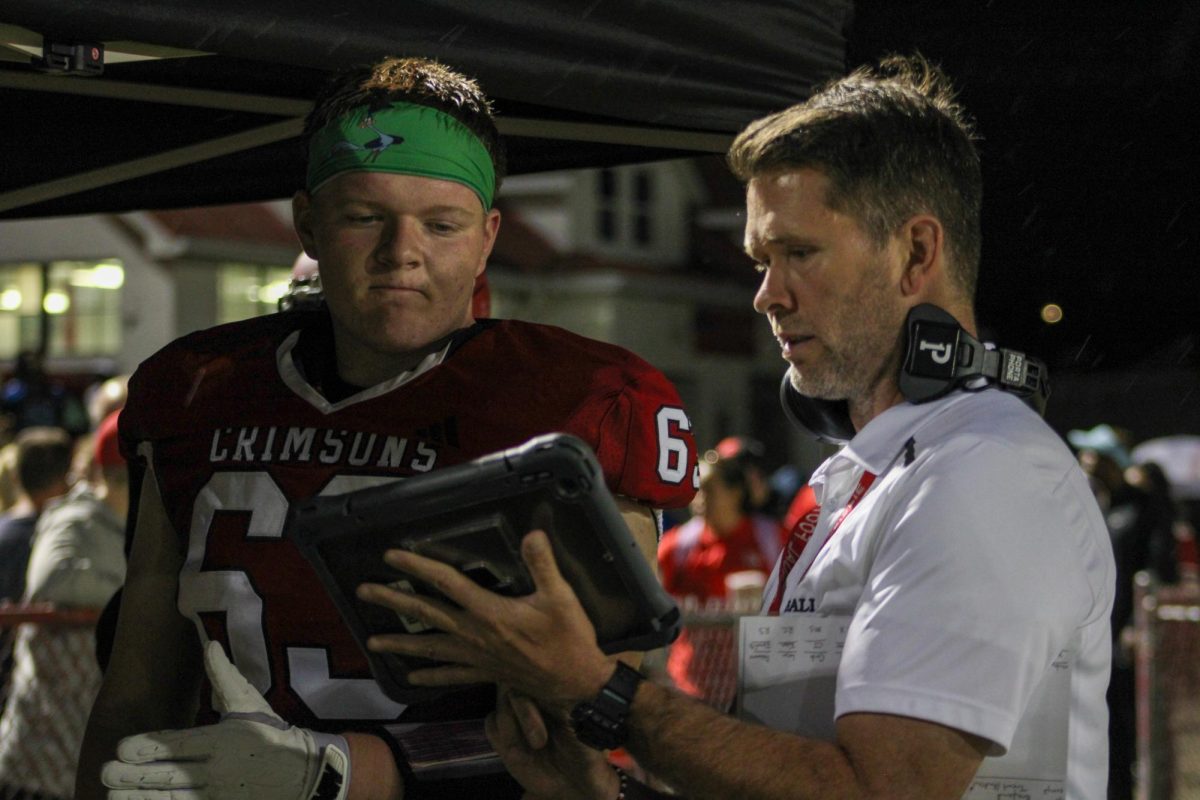 Coach Josh Gillispie and Kaedin Quirin (#63,12) review film before heading back on the field.