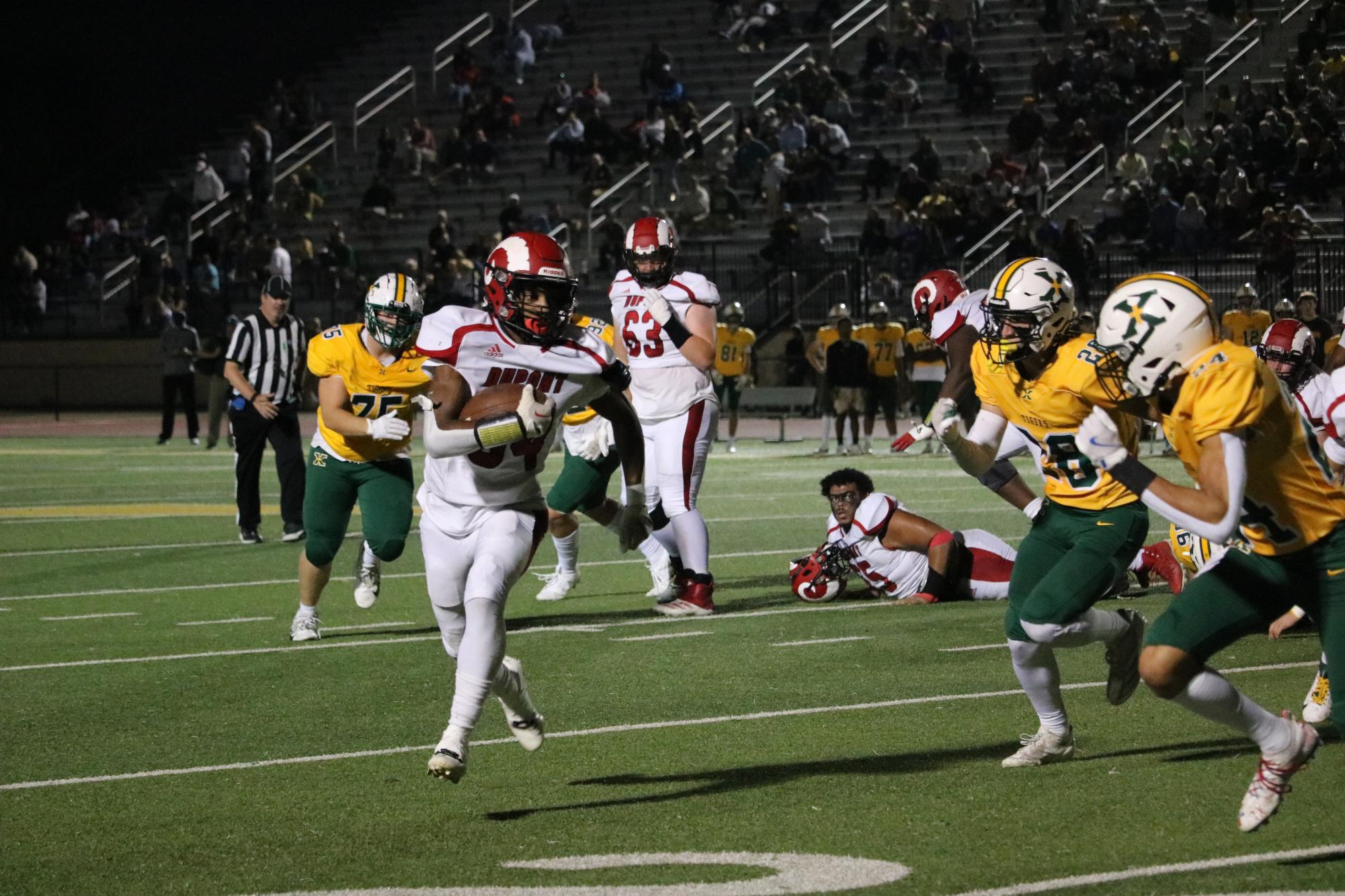 Gerian Traynor (#34, 11) runs with the ball in his hand, evading St. X defensivemen.