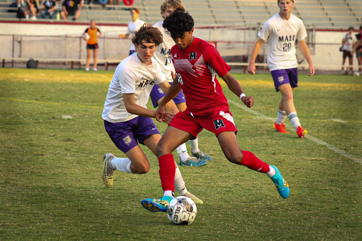 Ibrahim Piracha dribbles the ball away from a Male player during the annual rivalry soccer game. 