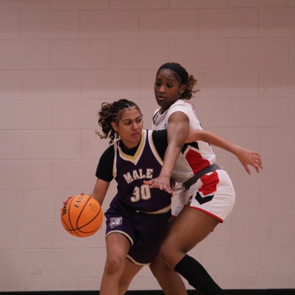 Amaria Pegues (#23, 9) defends against a Male player near the basket.