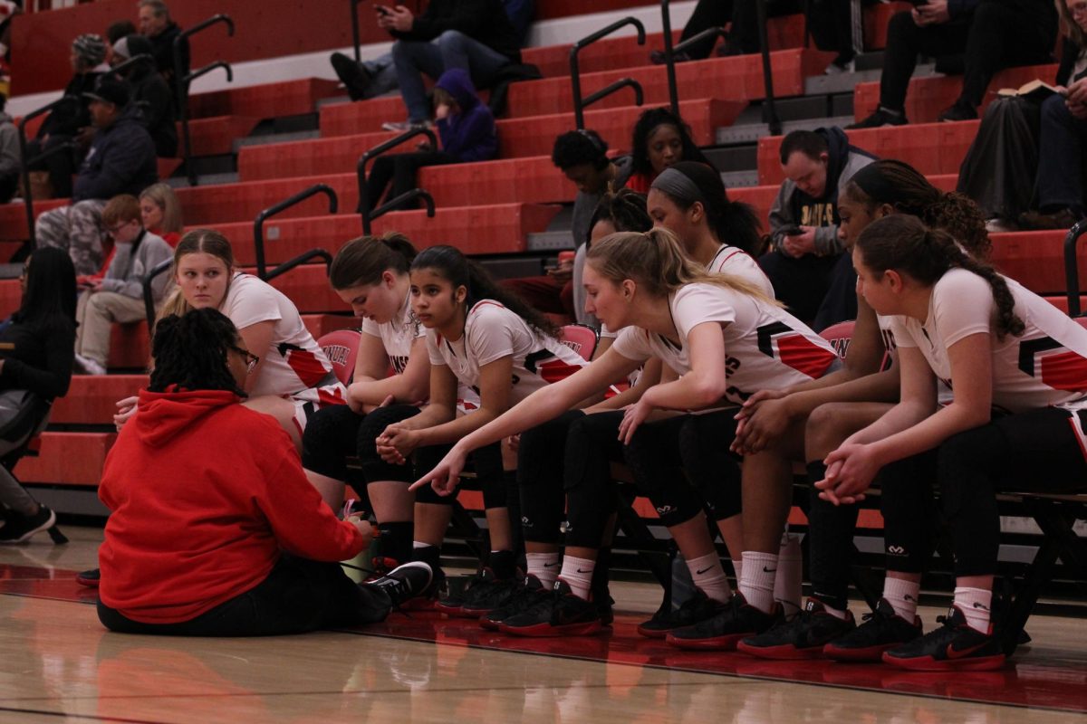 Lady Crimsons listening to coach during halftime.