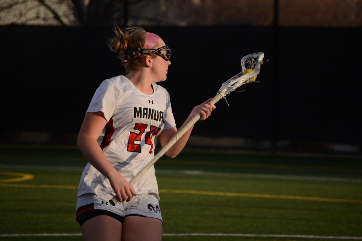 Molly Burke (#24, 11) looks around to pass the ball to another Manual player. 