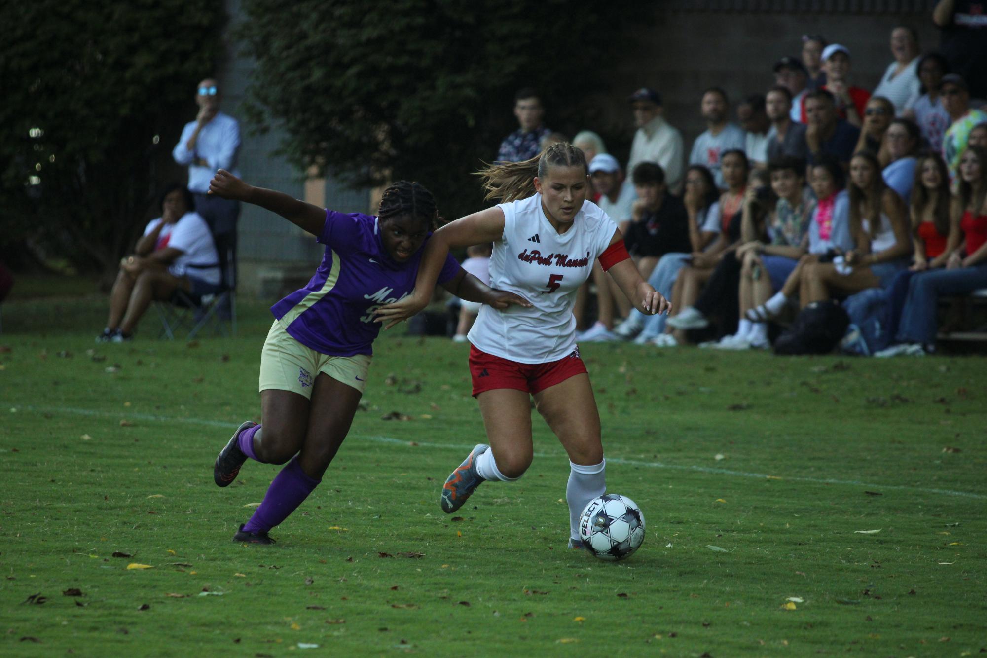 Chloe Groemling (#5,12) fights for the ball against Male defender.