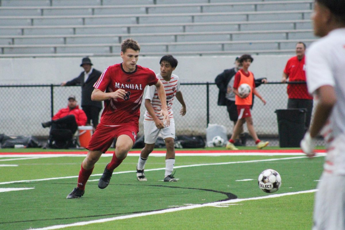 Jackson Bean (#8, 12) running down the field while kicking the ball.