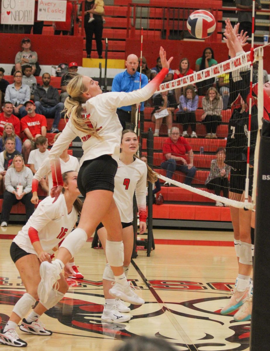 Avery Easley (#4, 12) attempting to hit the ball over the net. Photo courtesy of Derek Bush.