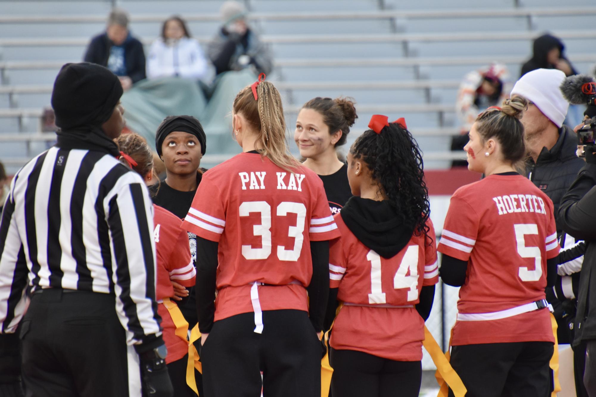 Senior and junior team members watch the coin to begin the match.