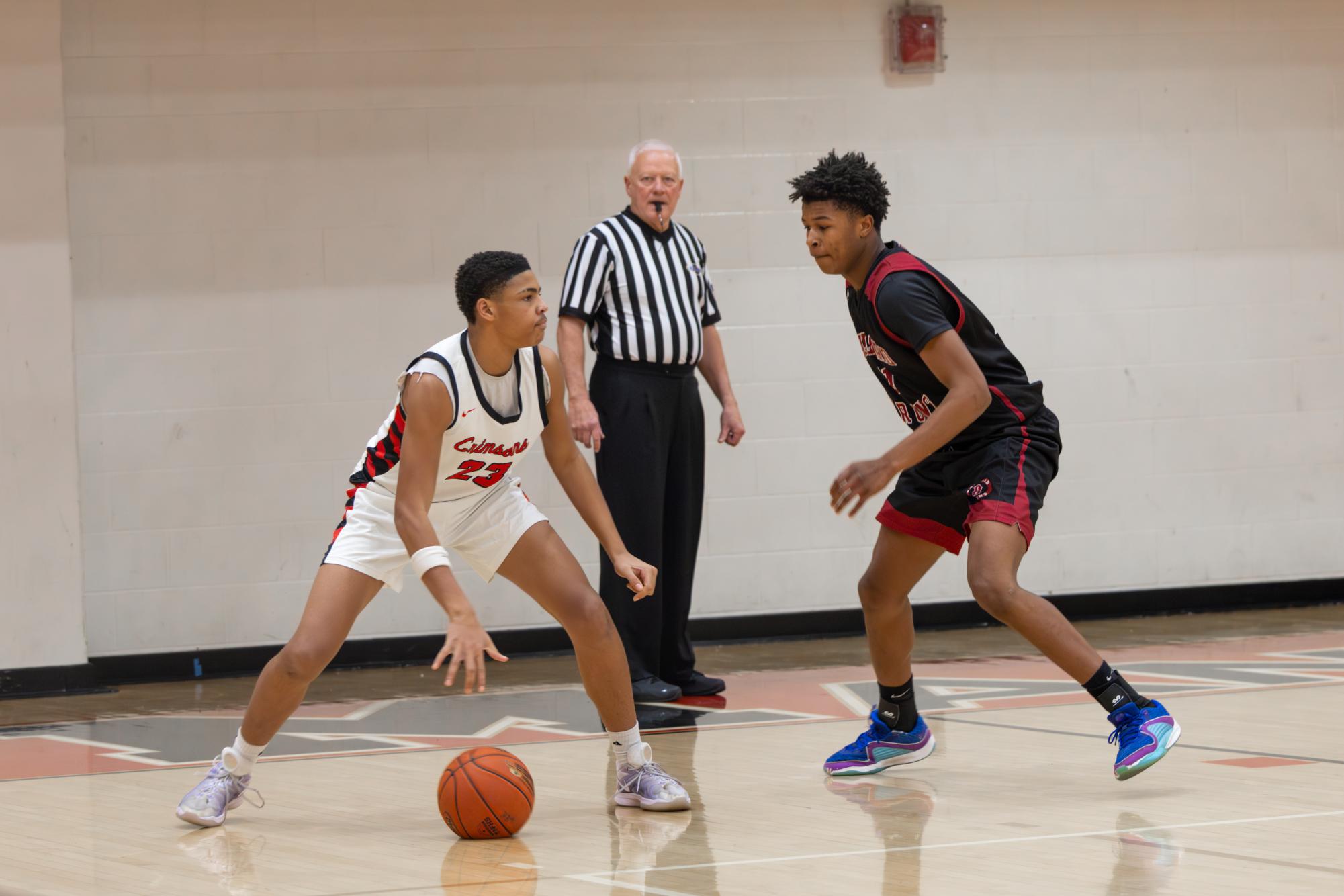 Levi Persely (#23, 9) attempts to move past a defender as the referee observes the play.
