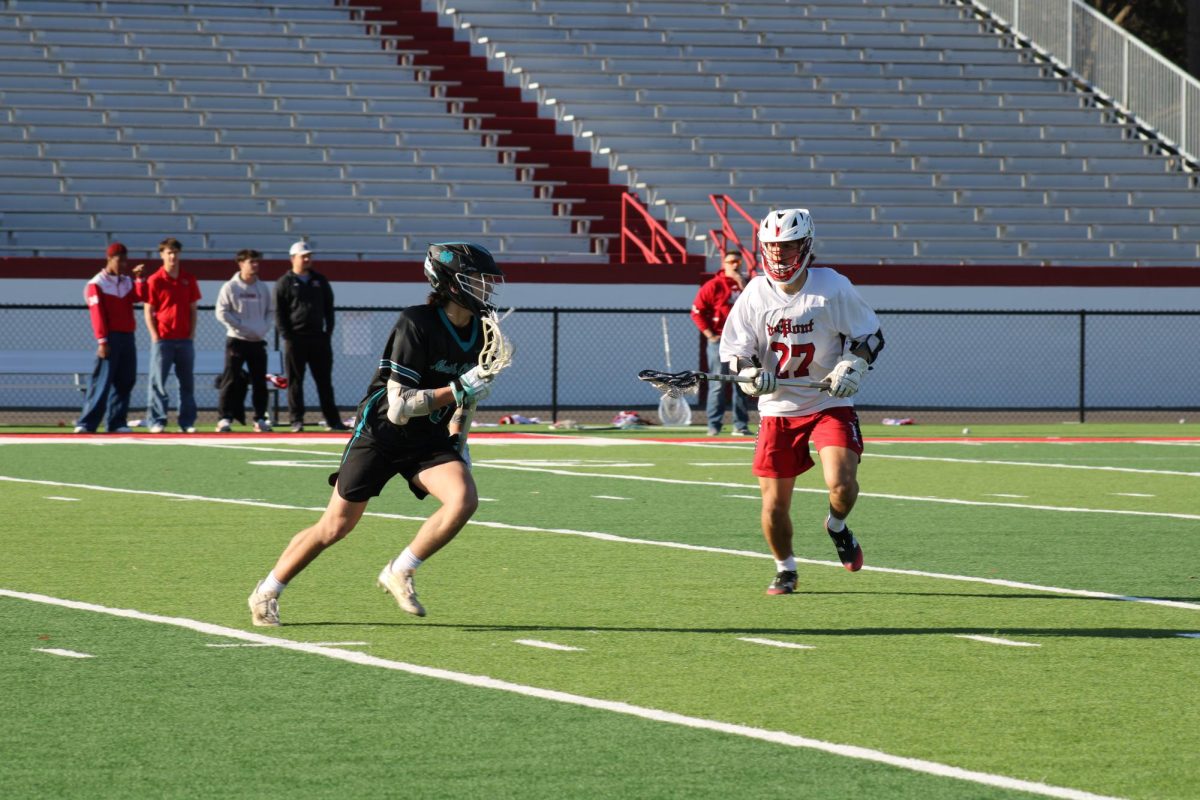 Owen Singer (#27, 11) trying to run around a North Oldham defense player