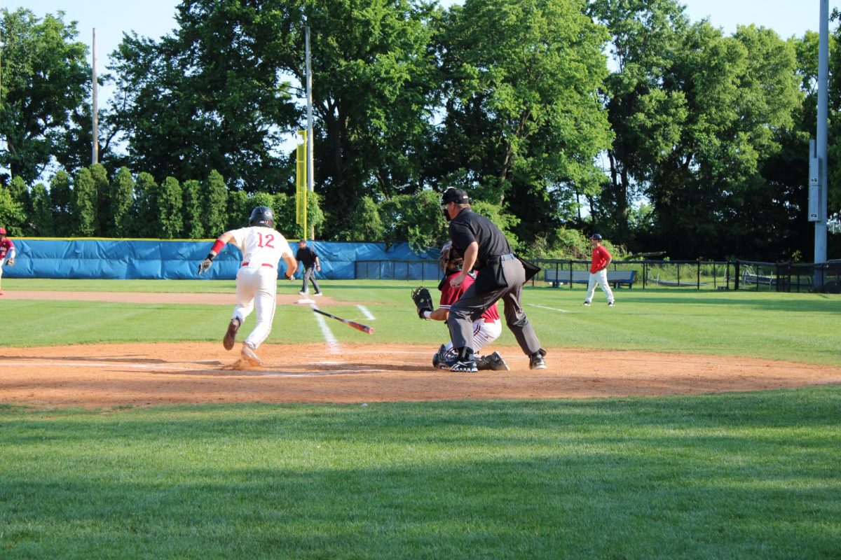 Aiden Jenkins (#12,11) hits a fly ball and makes a run to first base.